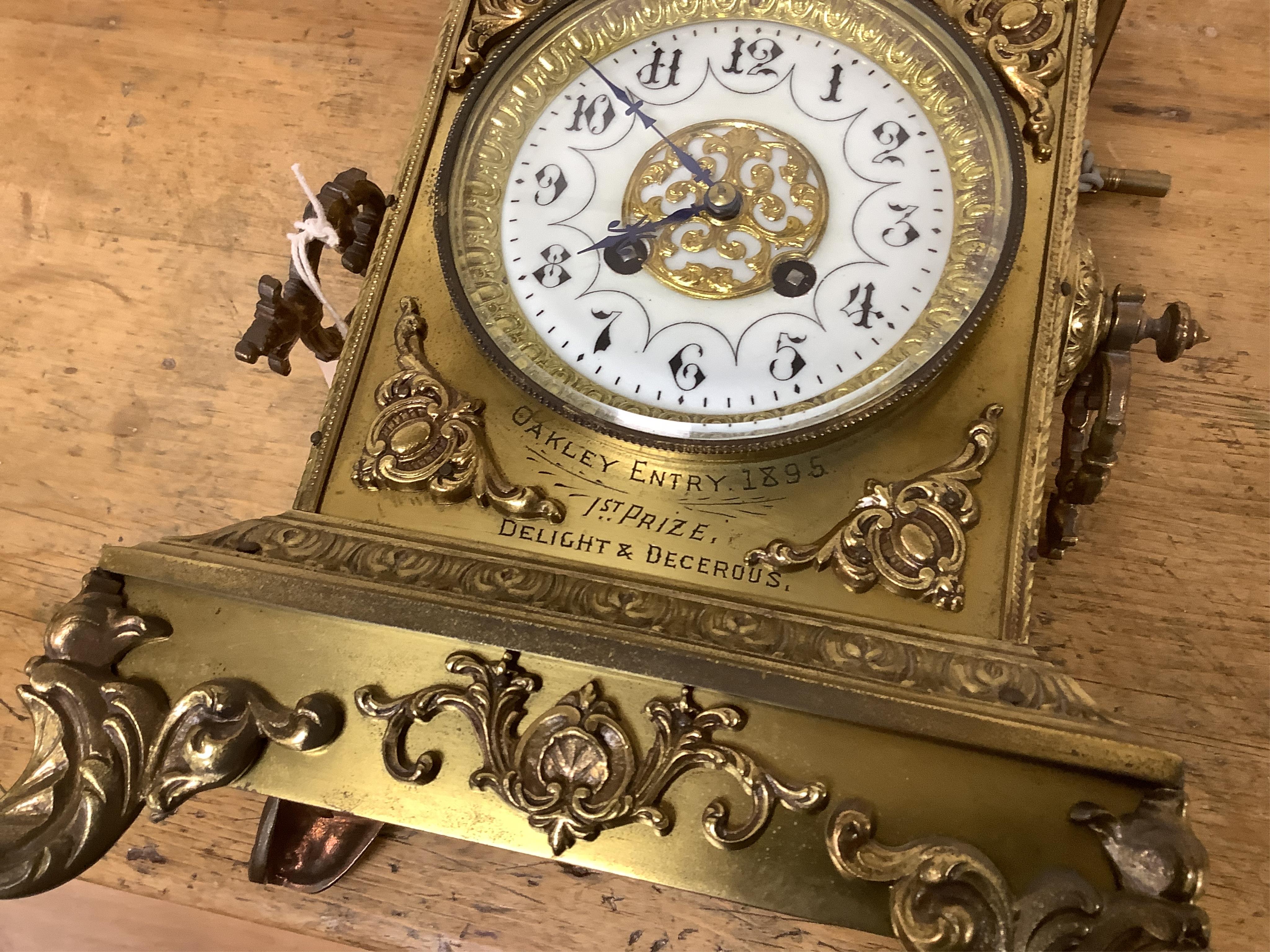 A decorative brass mantel clock with urn surmount, with 1st prize engraved panel, 41cm high